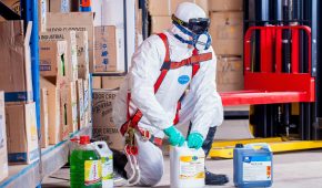Industrial worker in protective gear handling chemicals in a warehouse environment.